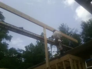 Carpenter setting a ridge beam over a new addition frame — Ice Dam Removal by Roofing Brothers in Burgin