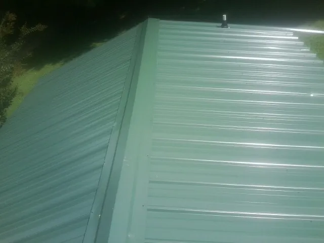 New green metal panels meeting at the ridge of a roof — Flat Roof Repair work by our crew in Burgin