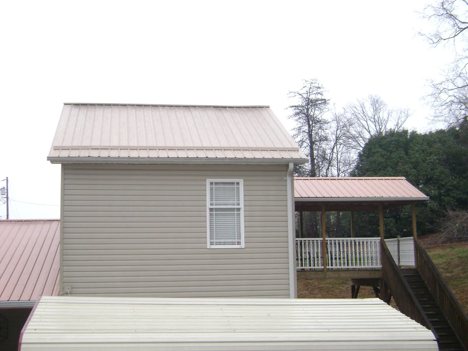 Tan metal roofs on a two story addition and attached porch, from a Roof Replacement job in Burgin