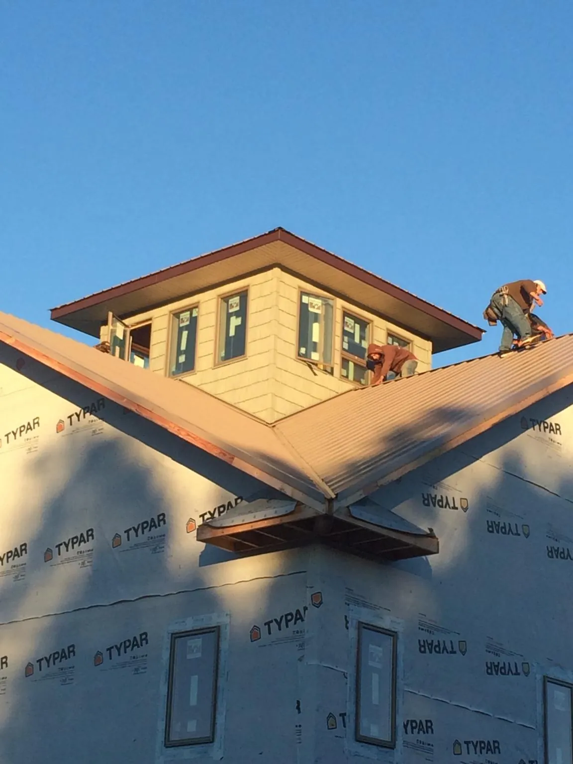 Roofers working around a rooftop cupola on a new metal roof at sunset — Roof Waterproofing in Burgin by Roofing Brothers